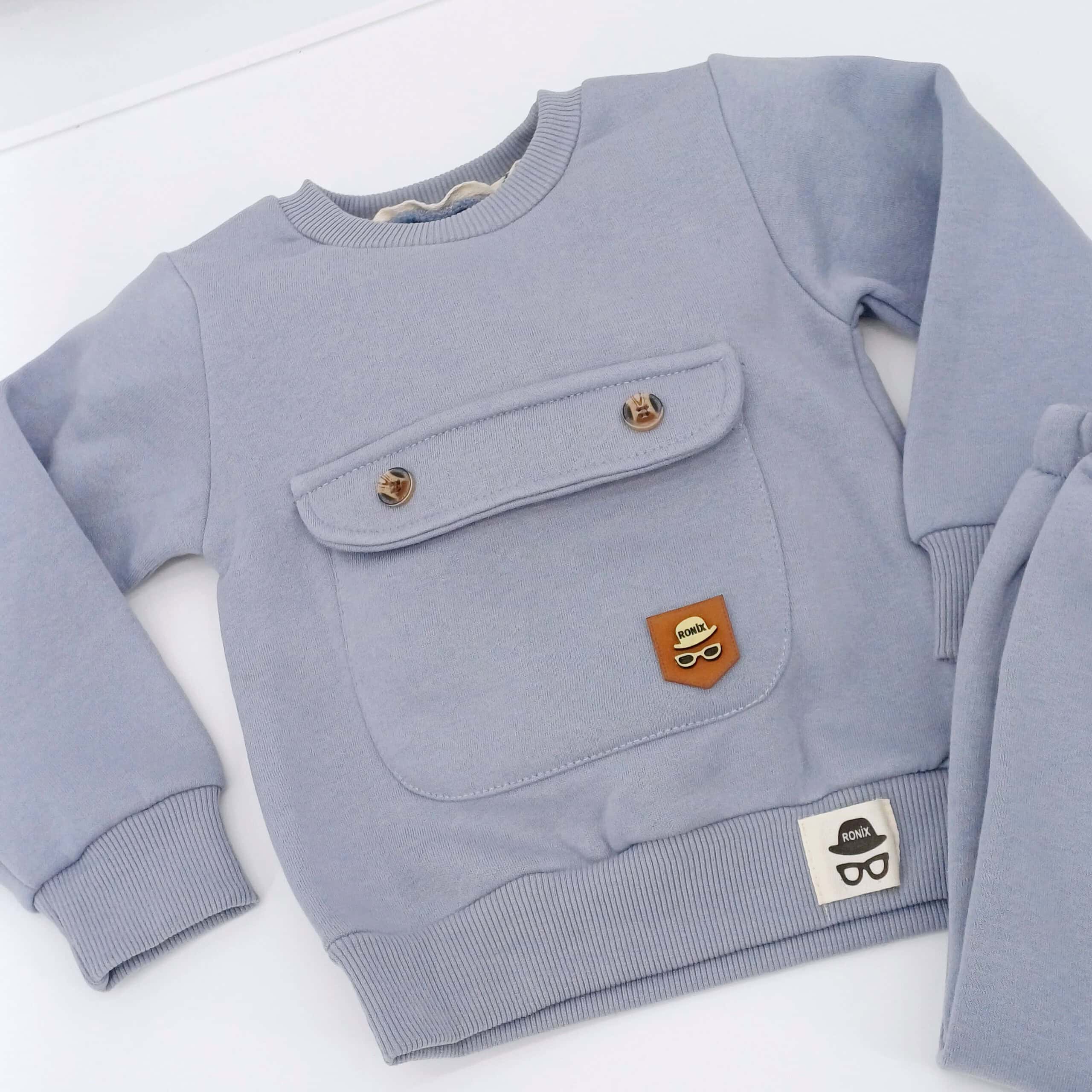 Ensemble hiver bébé gris avec pull et pantalon, doté d'une poche décorative et taille élastique. Disponible en tailles 9-12, 12-18, et 18-24 mois. Parfait pour garder votre enfant au chaud cet hiver.