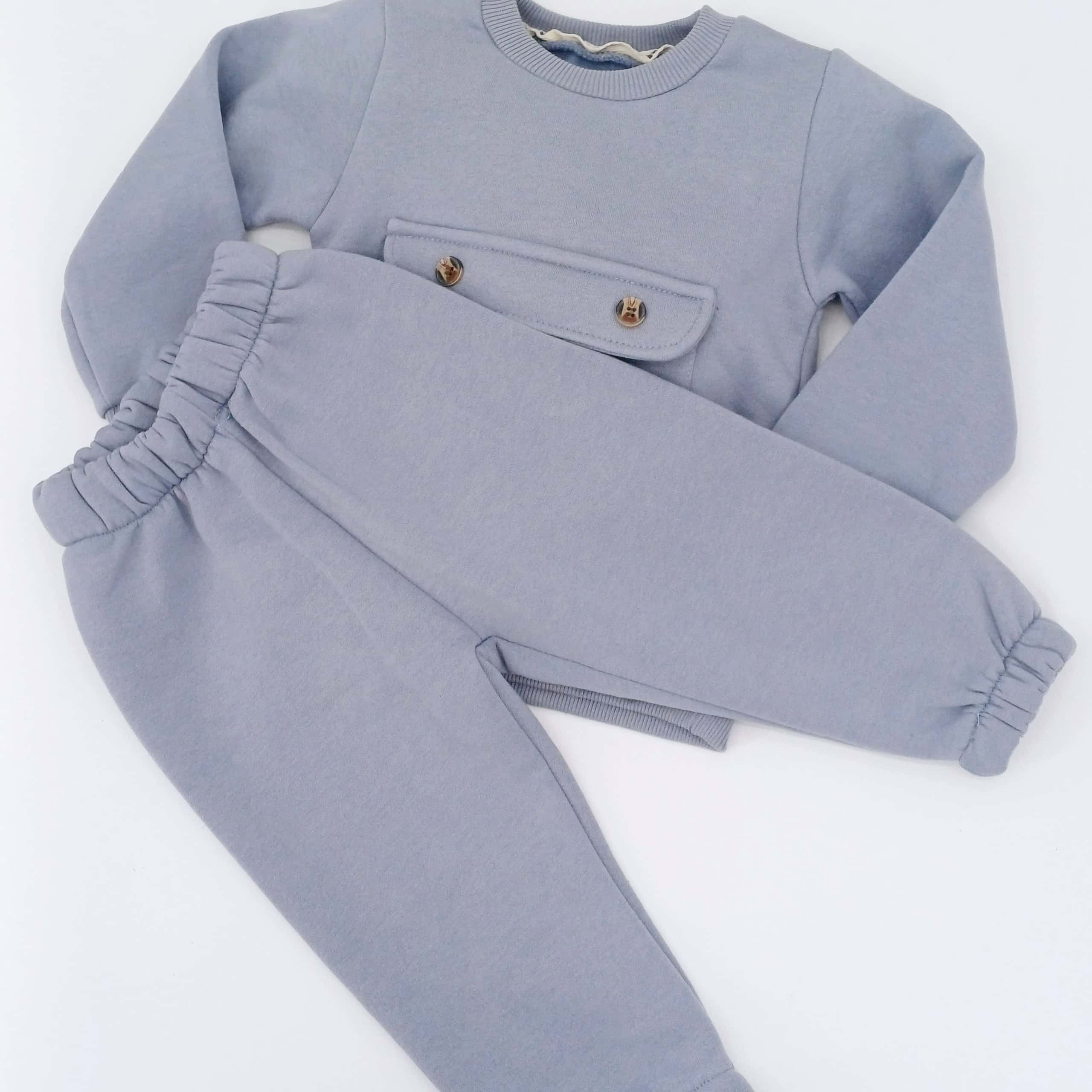 Ensemble hiver bébé gris avec pull et pantalon, doté d'une poche décorative et taille élastique. Disponible en tailles 9-12, 12-18, et 18-24 mois. Parfait pour garder votre enfant au chaud cet hiver.
